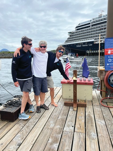 Alyosha Strum-Palerm, Jonathan McKee, and Matt Pistay of Team Pure & Wild celebrate their Race to Alaska victory by ringing the R2AK bell, officially marking their position as the 2022 winners.